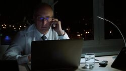Adult businessman calling to mobile phone while overtime work in night office Stock Footage
