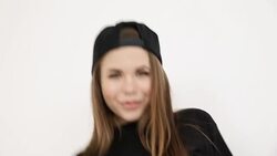 a teenage girl in black hip-hop clothes and a cap dances at the white wall- close-up, handheld shoot, small depth of field Stock Footage