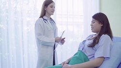 Beautiful smart Asian doctor and patient discussing and explaining something with clipboard in doctor hands while staying on Patient's bed at hospital. Medicine and health care concept. Stock Footage