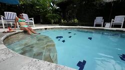 Young Italian girl sitting at the pool edge in a private villa in Bali Stock Footage