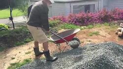 Adult Senior Man Filling a Wheel Barrel with Gravel Stock Footage