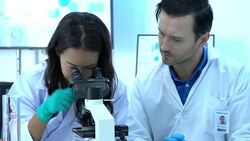 Scientist is looking through microscope with colleagues working in modern laboratory or medical center together. Concept of science, testing development and lab industry. Stock Footage
