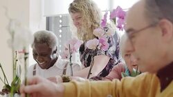 Instructor helping active seniors learning to arrange orchid flowers Stock Footage