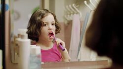 Little girl brushing her teeth in front of the mirror Stock Footage