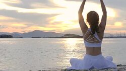 Happy young woman relaxing by practicing yoga on the beach at sunset, Sunrise background. Fitness, sport, yoga and healthy lifestyle concept. Stock Footage