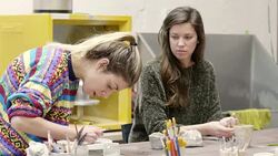 Student looking at teacher making clay container Stock Footage