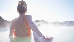 Follow me POV - Couple in love having fun. Boyfriend following girlfriend holding hands in Iceland outdoors in nature laughing and smiling enjoying geothermal spa in hot springs blue lagoon thermal baths Stock Footage