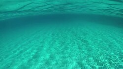 HALF UNDERWATER: Cinematic shot of the sandy ocean floor and scenic island. Stock Footage
