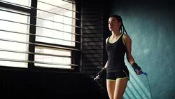 Young purposeful serious female boxer in wrapped bandage fist hands jumping on skipping rope in gym Stock Footage