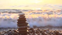 Pyramid of pebbles at sea in sunrise Stock Footage