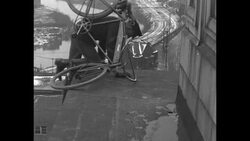 "Zip" rides bicycle along ledge and stands on top of building News Clip