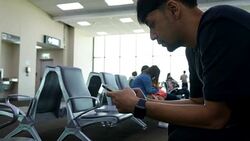 Young Asian man using mobile phone touchscreen and talking on phone. working on the phone, in the background of a Airport , planes, Concept: new business, travel, communication. Stock Footage