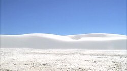 MEDIUM ANGLE OF DESERT LANDSCAPE. BLUE SKIES AND SAND DUNES. ROMAN CHARIOTS RACES BY CAMERA FROM LEFT TO RIGHT. TWO SOLDIERS ON HORSEBACK FOLLOW. COULD BE CHASES. Stock Footage