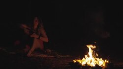 Beautiful young hippie woman with dreadlocks playing on djembe. Funky woman drumming in nature on an ethnic drum with a human skull at night. Slow motion Stock Footage