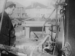 Boy with machine outside and a man fries bacon and eggs on a spade/shovel over an open fire Stock Footage