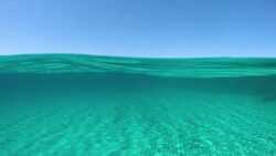 HALF UNDERWATER: Spectacular shot of the distant island in the middle of ocean. Stock Footage