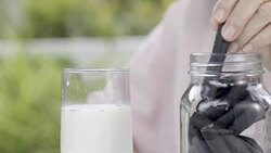 elderly hand dipping and stir a chocolate cookie In milk glass Stock Footage