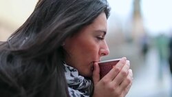 Woman blowing to cool down hot drink. Girl drinking warm beverage during cold season while in contemplation Stock Footage