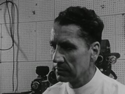 RAIN EXPERIMENTS: Dr. Jose Delgado observing Macaques monkeys w/ brain implants in glass cage, male hands holding transmitter control box, monkey backing up & jumping. Animal testing, scientific research, tests, motor control Instructional Video