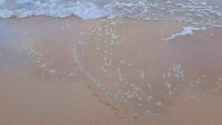 Heart on beach shot of Waves Rolling Up White Sand Beach with soft smooth foam bubble sea water background. Stock Footage