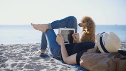 Woman traveler is holding touch pad, while is relaxing outdoors during his trip on the sea. Stock Footage