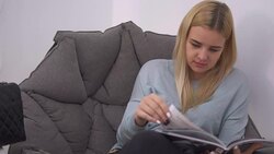 Beautiful girl thumbs a magazine in the chair Stock Footage