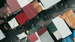 aerial drone footage of the morning city market with colorful tents looking down Stock Footage