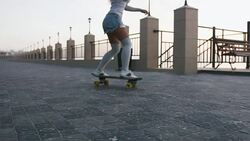 Young stylish attractive woman skateboarding at sunrise on seafront, slow motion Stock Footage