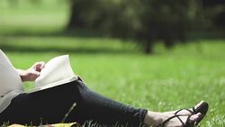 Female expecting child resting in park and reading book about care of newborn Stock Footage