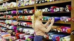 girl choosing fabric among diversity on shelves in store Stock Footage
