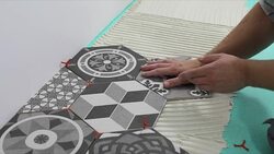 tiler laying hexagon floor tiles in home bathroom Stock Footage