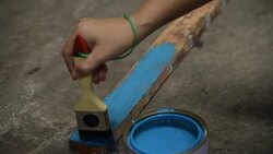 Human hand is painting blue color on wooden stick Stock Footage
