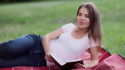 cute young girl reading a book in the park - portrait with Bible - HD video Stock Footage