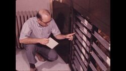 1970s: Man crouches down, opens cabinet, and pulls open drawer containing two rows of stuffed birds Stock Footage