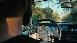 young man driving a 4x4 vehicle car in a forest area with some bush and trees next to the dirt road Stock Footage