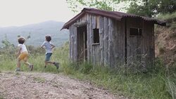 Cute siblings running out of log cabin Stock Footage