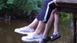 Teens relaxes by the river sitting on the edge of a wooden jetty. Stock Footage