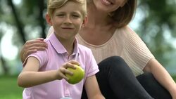 Little boy and caring mother holding apple, family stands for healthy nutrition Stock Footage