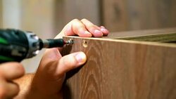 Fastening the panel with a screw using a screwdriver. Hand screwdriver in operation. furniture Stock Footage