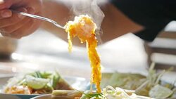 Pad Thai, the most famous and well-known fast food restaurant in Thailand. Man holding a spoon with noodles with smoke. Pad thai The food is hot and tasty. Stock Footage