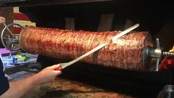 a Cook cutting doner kebab with big sharp doner knife, Turkish Doner Kebab turning around grill Stock Footage