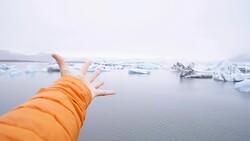 Hand stretches towards glacier lagoon icebergs, people environment conservation nature concept Stock Footage