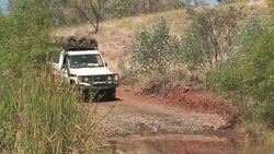 SUV travels the dirt road, drives through water. Editorial Use Only. Stock Footage