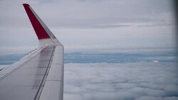 Airplane flight. Wing of an airplane flying above the clouds from window plane view Stock Footage