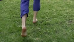 Barefoot man running on green grass in slow motion Stock Footage