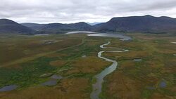 Flying over River in Tundra to Mountains Stock Footage