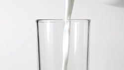 Close-up pouring fresh milk from the jug on white background Stock Footage