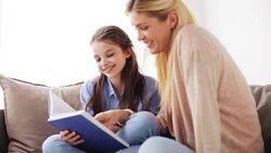 happy girl with mother reading book at home Stock Footage
