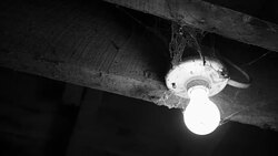 Panning to a light bulb covered in cobwebs - horror concept - black and white version Stock Footage