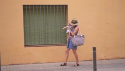 Woman walking in the street and carrying baby girl Stock Footage